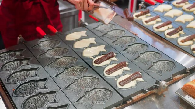 Tokyo, Japan - Oct 14 2024, 4k, close-up view of wide cast-iron frying pan with molds used to fry traditional Japanese fish-shaped treats called taiyaki at Tokyo street cafe, without people, Tokyo, Ja