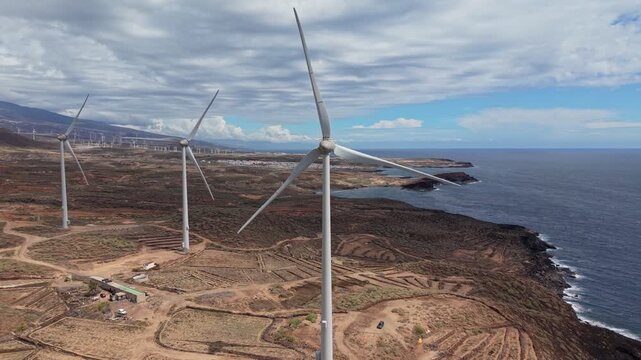 Aerial drone footage of a wind farm in Tenerife, Canary Islands, featuring rows of wind turbines generating renewable energy across a rugged volcanic landscape