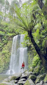 Adventurer girl stands close to and admires the powerful Beauchamp Falls in Great Otway National Park, Victoria, Australia, most beautiful waterfalls located near Melbourne
