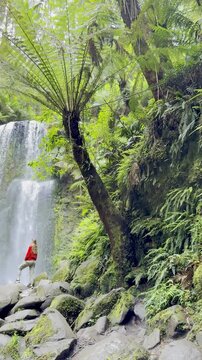 Adventurer girl stands close to and admires the powerful Beauchamp Falls in Great Otway National Park, Victoria, Australia, most beautiful waterfalls located near Melbourne