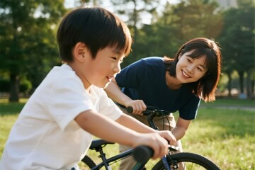 Obraz premium A woman helps a young boy learn to ride a bicycle in a sunny park.
