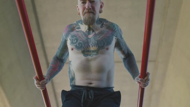 Tattooed athlete doing dips on parallel bars