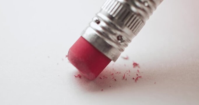 Closeup of pink pencil eraser erasing and creating a mess on white paper. Conceptual bad idea, fixing problems, failure or mistake, wrong decision, or to remove an error. Back to School supplies.