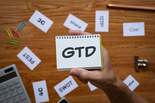 Eye-catching image of GTD text on notebook. The word stands for Getting Things Done. Shown with calculator, clips.