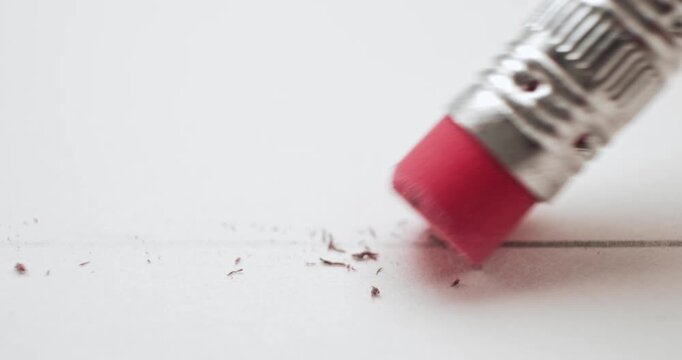 Erasing a pencil line with a pink eraser and creating a mess on white paper. Conceptual bad idea, fixing problems, failure or mistake, wrong decision, or to remove an error. Back to School supplies.