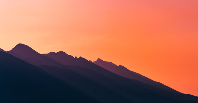 Golden Horizon: Layered Mountain Silhouettes at Sunset