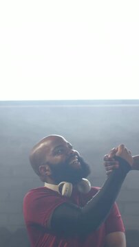 Vertical video: Smiling man red shirt headphones holding hand entering right under panel, greeting