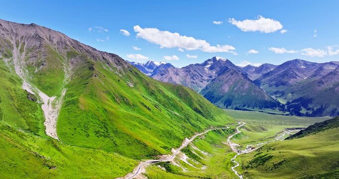 Aerial view of a winding road on steep green mountain slopes, Xinjiang, China.