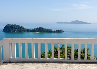 Gulf of Thailand with islands near Chumphon. Turquoise waters and distant landmasses under clear skies. White railing overlooking the scenic seascape.