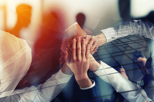 Diverse business professionals stacking hands together in unity, symbolizing teamwork, collaboration, and successful partnership in corporate environment.