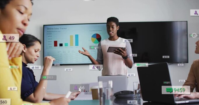 Presenter gesturing with tablet at conference table, initiating UI online sales charts for update