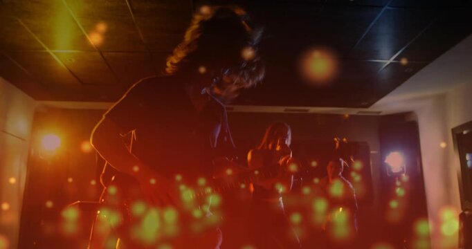 Cam pulling back revealing band rehearsing, guitarist playing, singer singing, particles overlaying
