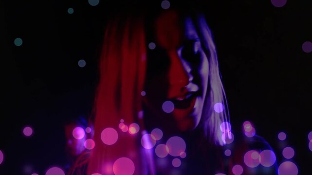 Female performer responding to music cue, mouthing lyric while turning, magenta bokeh across face