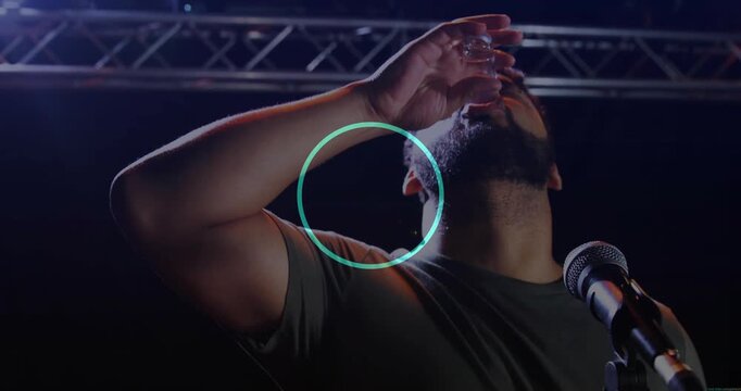 MC on mic lifting shotglass sparking blue dots drinking wincing toasting shouting for entertainment