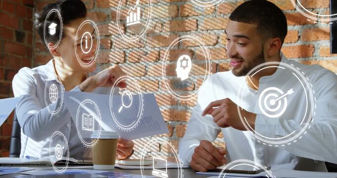 Woman and man reviewing report in business meeting, animated icons floating over pair, fist-bumping