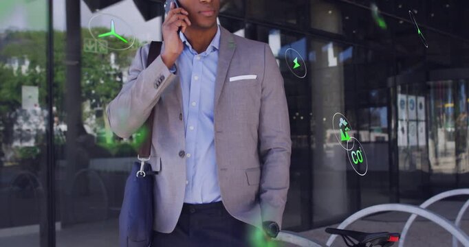 Vertical video: Mid adult man taking phone call, green energy icons floating, visualizing eco goals