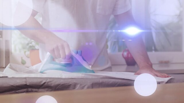 Adult male placing iron onto shirt, gliding iron smoothing wrinkles while light flares