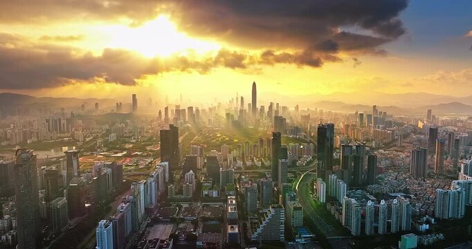 Aerial view of a dense modern skyline with skyscrapers under golden sunlight and sunbeams, Shenzhen, China