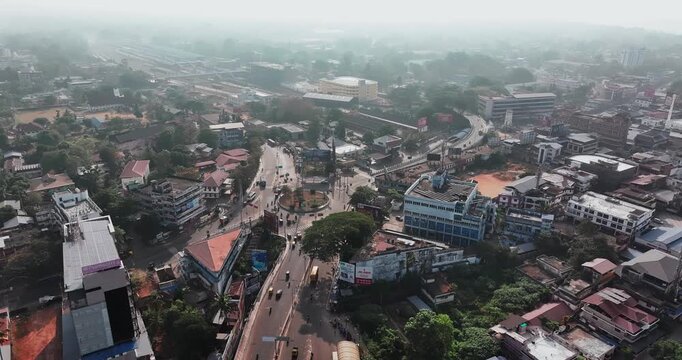 Aerial view of car traffic at the roundabout, lane and buildings in Thiruvananthapuram, Kerala, India. Beautiful cinematic shot of an Indian City.