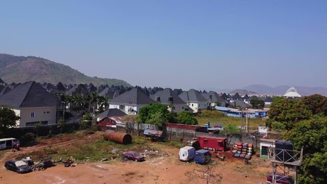 Drone flying over shacks towards a walled wealthy suburban neighborhood in Abuja, Nigeria showing a large contrast between rich and poor in the African country