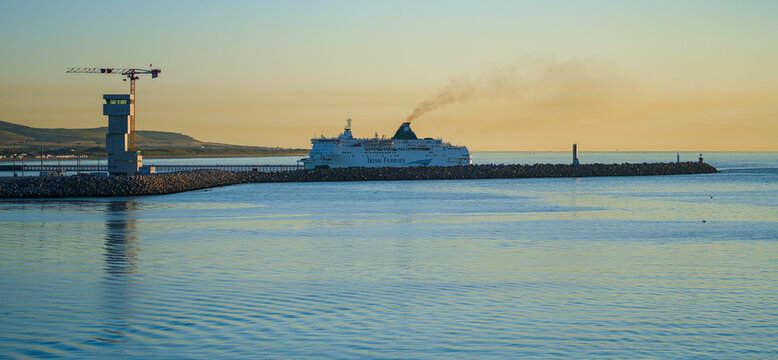 An Irish Ferries vessel departing the Port of Calais at sunset with visible exhaust smoke