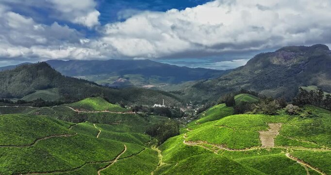 Cinematic long aerial view of Tea Plantation hill valley in Munnar, Kerala, India. Aerial view of a tea plantation in Munnar. The beautiful Western Ghats mountain range in Kerala