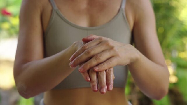 Woman applying skincare cream to elbow in outdoor natural setting