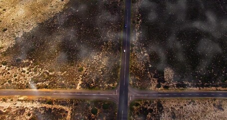 Naklejka premium Showing four-way paved intersection crossing arid scrubland with grid markers and light vehicle