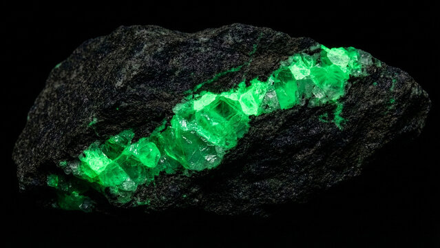 Rough dark rock with a glowing green crystal vein running through it