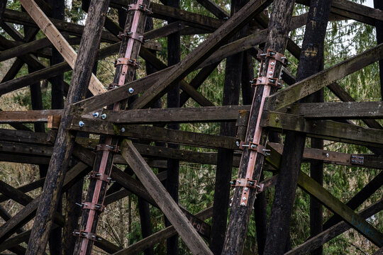Galvanized iron pole splint, reinforcing metal with collar clamps on old wooden train trestle structural support beams, maintenance and repair patch for added stability and safety
