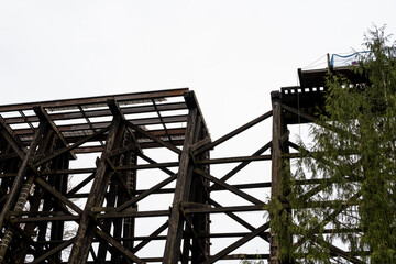 Naklejka premium Old Wilburton wooden railway trestle bridge, out of service, with train tracks and section of bridge missing, deathtrap safety hazard, mind the gap 