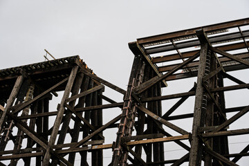 Naklejka premium Old Wilburton wooden railway trestle bridge, out of service, with train tracks and section of bridge missing, deathtrap safety hazard, mind the gap 