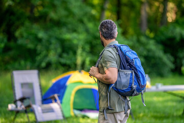 Naklejka premium Man at camp picnic in forest. Man hiking on summer day. Summer camp activity. Summer camping retreat. Camp adventure. Hiking lifestyle. Man at campsite. Picnic time, copy space