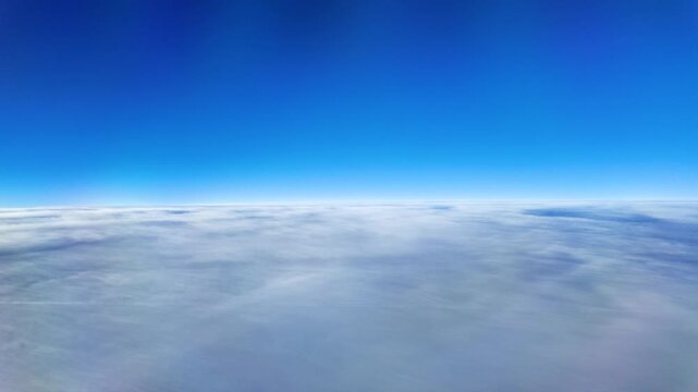 View from an airplane window showing clouds and sky. Travel and aviation concept with aerial perspective above the clouds. Peaceful atmosphere, journey and transportation theme.