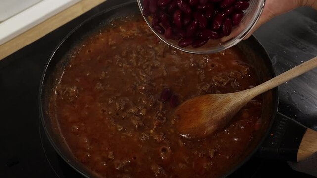 Next step to pouring red beans into the simmering browned meat sauce on stovetop.