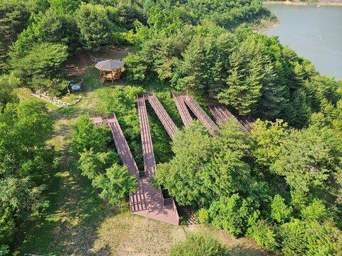 Aerial view of a zigzag wooden walkway and pavilion in the lush forest of Yecheon, South Korea