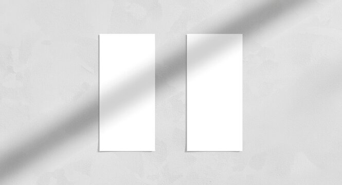 Two clean vertical rectangle menu mockups with soft shadow casts diagonally aligned on a neutral light grey concrete texture flat lay