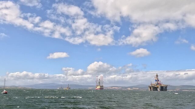 Oil Rigs and Distant Boats on Choppy Sea Under Cloudy Sky