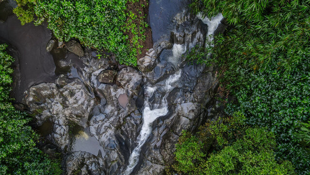 Aerial view of Clear mountain stream running through a rocky riverbed, Nature landscape with a babbling brook and vibrant green foliage