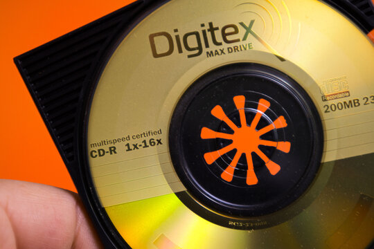 Digitec Max Drive CD-R disc with multispeed certification held in hand on an orange background