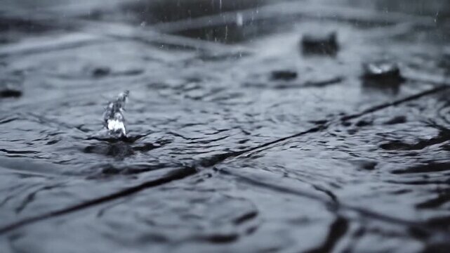 Raindrops creating ripples on a tiled surface during a downpour