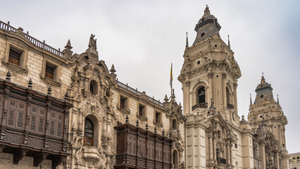 Fototapeta premium Old Spanish Colonial Revival architecture. Basilica and Convent of San Francisco. Columns, arches, stone carvings, statues on the facade. Wooden barred balconies. Domes, crosses against the sky. Peru