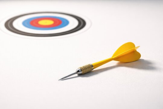 Yellow dart missing the mark on a clean white surface concept