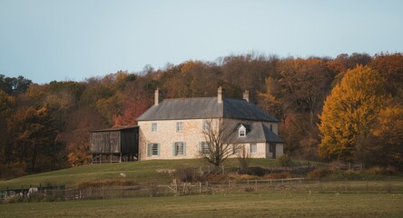 Fototapeta premium Historic countryside farmhouse on a hillside surrounded by autumn trees
