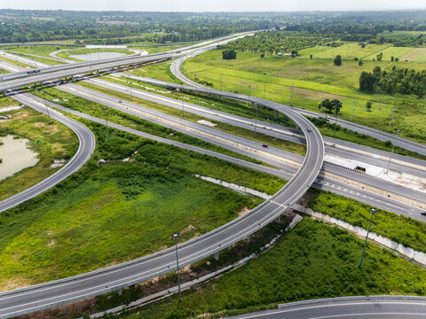 Drone shot a large highway interchange crossing over green farmlands in Thailand