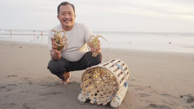 portrait, smiling balinese fisherman caught two spiny lobsters with bamboo trap or pot in tabanan, bali, indonesia, southeast asia, looking at camera, indonesian people