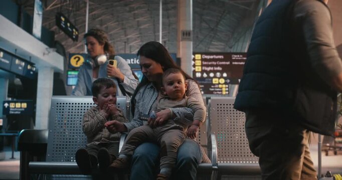 Family Reacts to Boarding Call. After Long Wait, Young Family With Two Toddlers Picks Up Luggage, Starts Walking Toward Boarding Gate. Family Travel Logistics, Transition From Waiting Lounge Airplane.