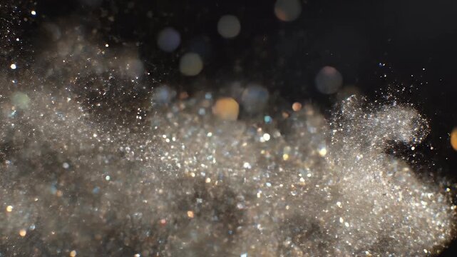 Close-up of a shimmering cloud of particles and colorful bokeh lights against black