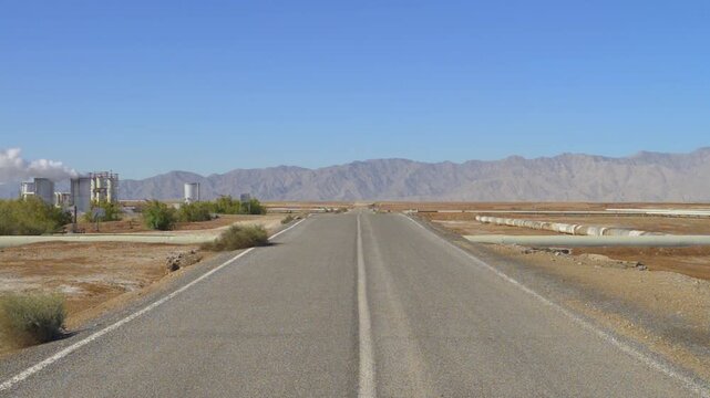 Campo geotermico en Mexicali Baja California Mexico. Zona de pozos para extraccion de vapor para generar energia electrica en el valle con cielo azul despejado y nubes sobre las monta&ntilde;as en el fondo