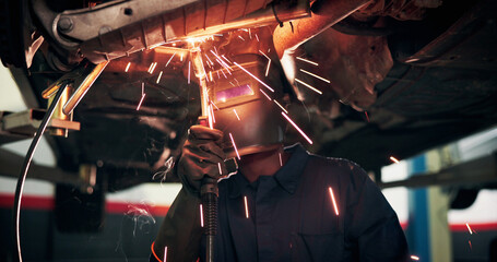 Fototapeta premium Mechanic, welding and person with tools by car for diagnostics, maintenance or auto service. Workshop, sparks and technician with equipment for vehicle inspection, fixing or engine repair with helmet